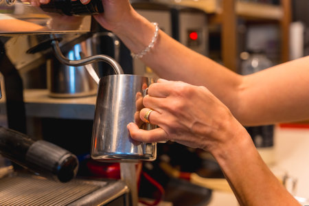 Unrecognizable female cafeteria waitress preparing coffee in a coffee machineの写真素材