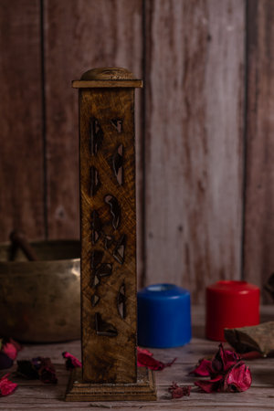 carved wooden incense burner with lighted colored candles and Tibetan bowl in the backgroundの写真素材