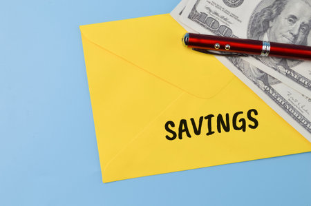 Money banknotes, pen and yellow envelope with text SAVINGSの写真素材