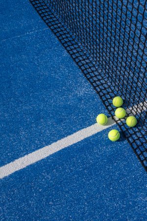 several paddle tennis balls by the net on a blue paddle tennis courtの写真素材
