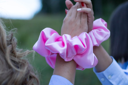 A back view of females with beautiful trendy scrunchies on their hands giving a high five