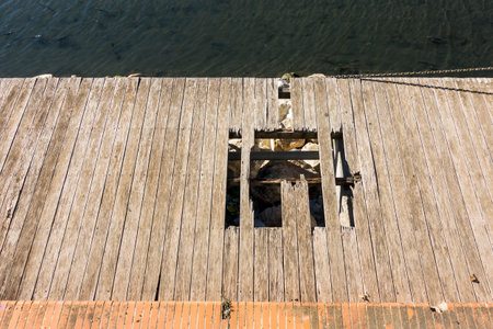 A wooden pier with a damaged part causing dangerous walkwayの写真素材