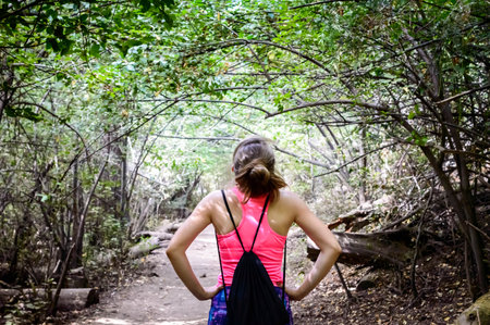 A rear view of a sexy hiker woman with a drawstring bag along the forest