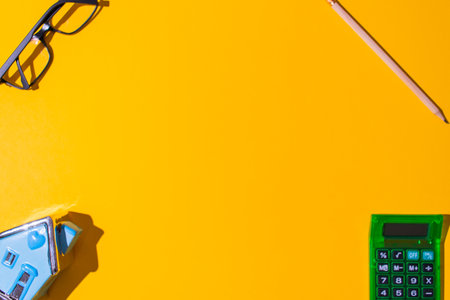 A top view of a neon orange surface with small stationery objects on it at each cornerの写真素材