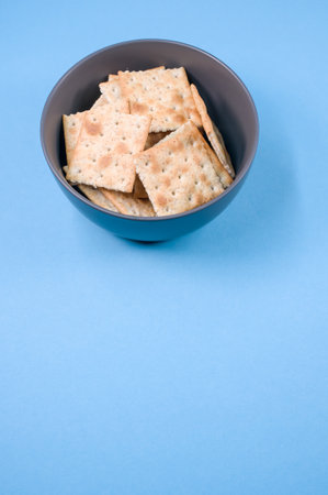 A vertical shot of square crackers on a bowl isolated on blue backgroundの写真素材