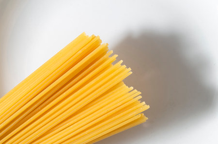 A high angle shot of a stack of raw spaghetti on a white surface