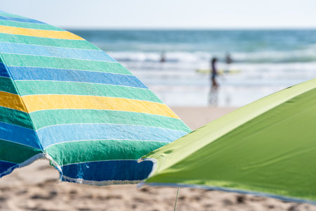 A colorful beach umbrella on the beach against the wavy sea on the coastの写真素材