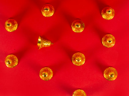 A top view of golden Christmas bells on a  red background