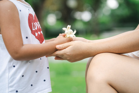 A beautiful view of a kid's hands giving small white flowers to her mommyの写真素材