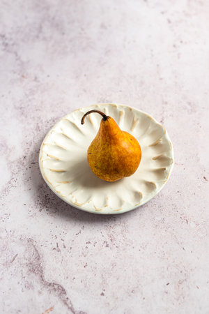 Organic Bosc Pear on white handmade ceramic plateの写真素材