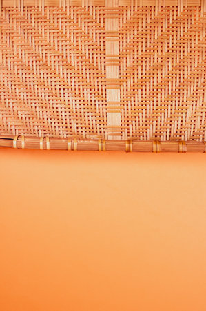 A vertical shot of bamboo wicker tray isolated on an orange backgroundの写真素材