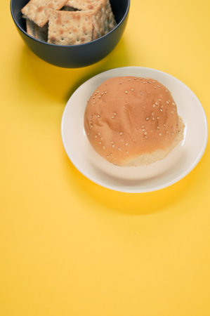 A vertical shot of a tasty bun and bread chips on a yellow backgroundの写真素材