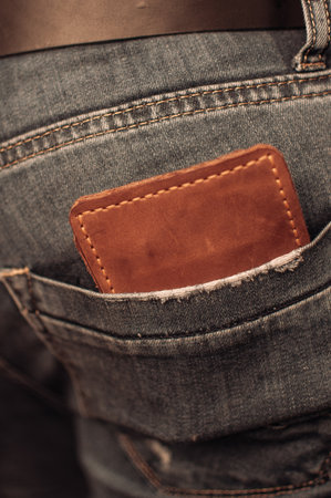 A closeup shot of a brown leather wallet in the jeans pocket