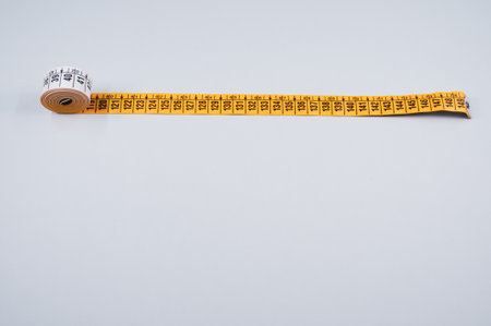 A closeup shot of a yellow measuring tape on white background