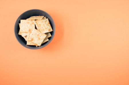 A top view of square crackers on a bowl isolated on an orange backgroundの写真素材