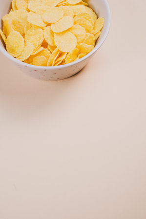 A bowl of cornflakes isolated on a beige background with free space for textの写真素材