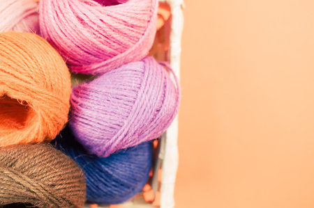 A basket full of colorful yarn rolls isolated on an orange background with free space for text