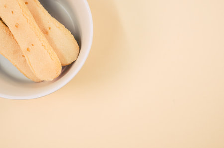 A high angle shot of bowl of cookies on an orange surfaceの写真素材