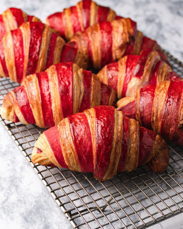 A vertical shot of delicious raspberry croissants on a net tray on the table