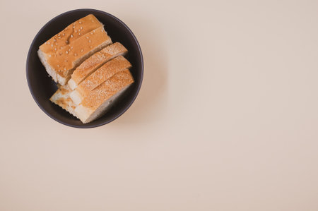 A bowl with bread slices isolated on a beige background with free space for textの写真素材