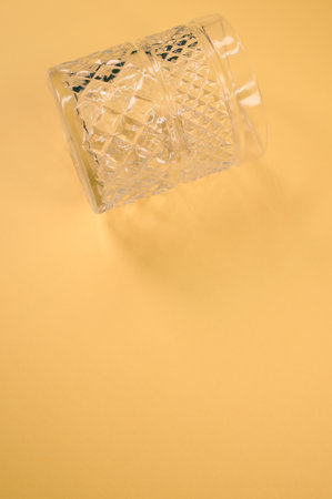 A vertical shot of crystal glass isolated on a yellow backgroundの写真素材