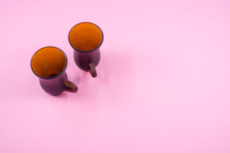 A top view of two brown bell-shaped mugs isolated on pink backgroundの写真素材