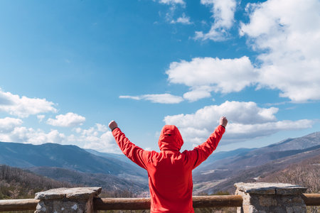 A caucasian male in a red coat looking at the beautiful cloudy skiesの写真素材