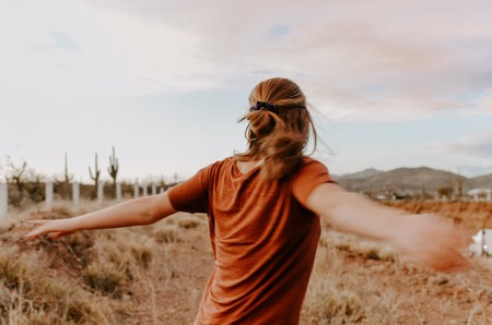 A vertical shot of a young, cute blond woman posing in a beautiful, way with her arms openの写真素材