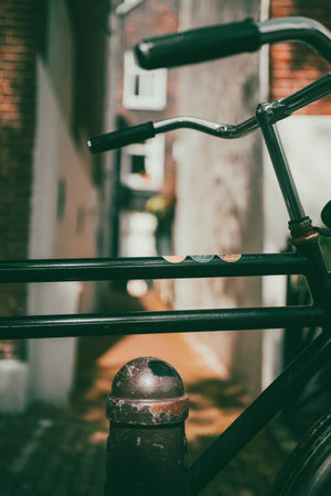 A vertical shot of a bicycle parked outdoors by a narrow alleyの写真素材
