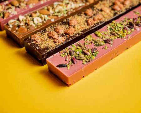 A closeup of chocolate assortment bars with different flavors on a yellow surface