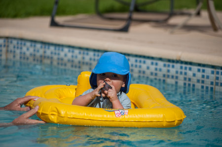 A closeup shot of a cute baby boy in an inflatable swimming ring in the outdoor pool on a sunny day
