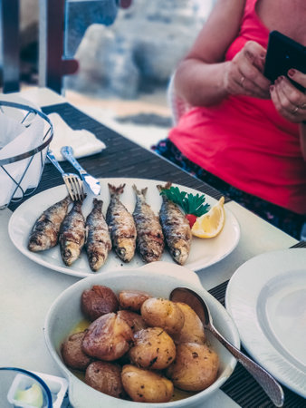 A vertical shot of many small fishes and homemade potatoes put on the table for the dinner.の写真素材