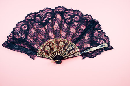 A closeup of a black fan with lace on pink background.の写真素材