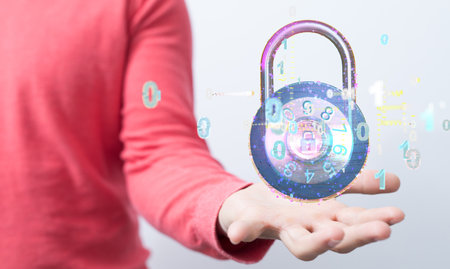 A hand holding a 3D render of a lock surrounded by binary codeの写真素材