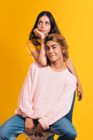 A vertical shot of a young stylish couple posing against a bright yellow backgroundの写真素材