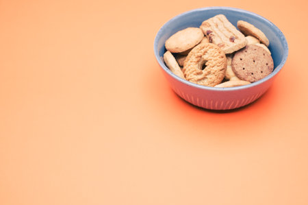 A closeup of a bowl of cookies on the orange background.の写真素材