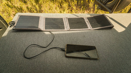 A closeup shot of a phone charging with a solar charger outdoorsの写真素材