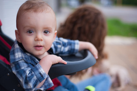 A closeup shot of a cute baby boy on a walk outdoors in a strollerの写真素材
