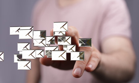 A 3D rendering of mail icons with a real person in the backgroundの写真素材