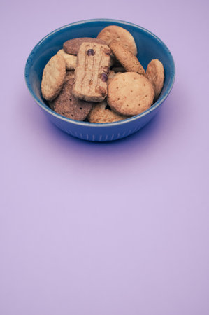 A vertical closeup of a bowl of cookies on the violet background.の写真素材
