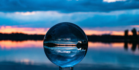 A closeup shot of a lens ball reflecting the landscape of a lake and trees