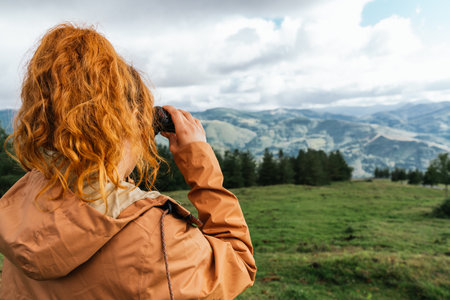 A caucasian female looking through binoculars at a landscapeの写真素材