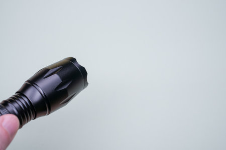 A closeup of a black flashlight on the gray background.の写真素材