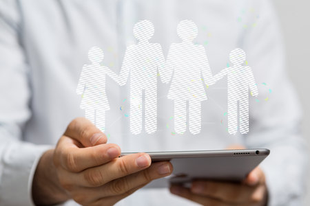 A person's hand holding a tablet with 3D rendered family silhouettesの写真素材