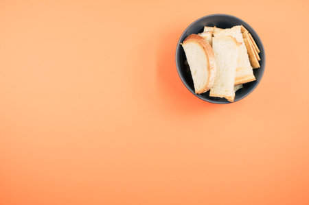 A top view of bread slices on a bowl isolated on an orangebackgroundの写真素材
