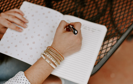 A closeup shot of a South Asian young woman hands writing something in the copybookの写真素材