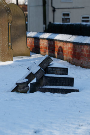 A gravestone with a Christian cross by a cathedral in the winter