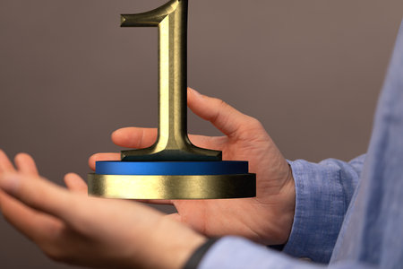 A hand holding a 3D decorative 1st place trophy signの写真素材