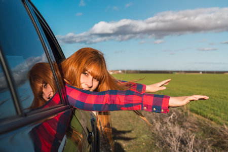 A caucasian female posing for a photo out of the window of a carの写真素材
