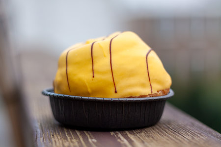 A delicious pastry in a mold with tasty icing on a wooden railing